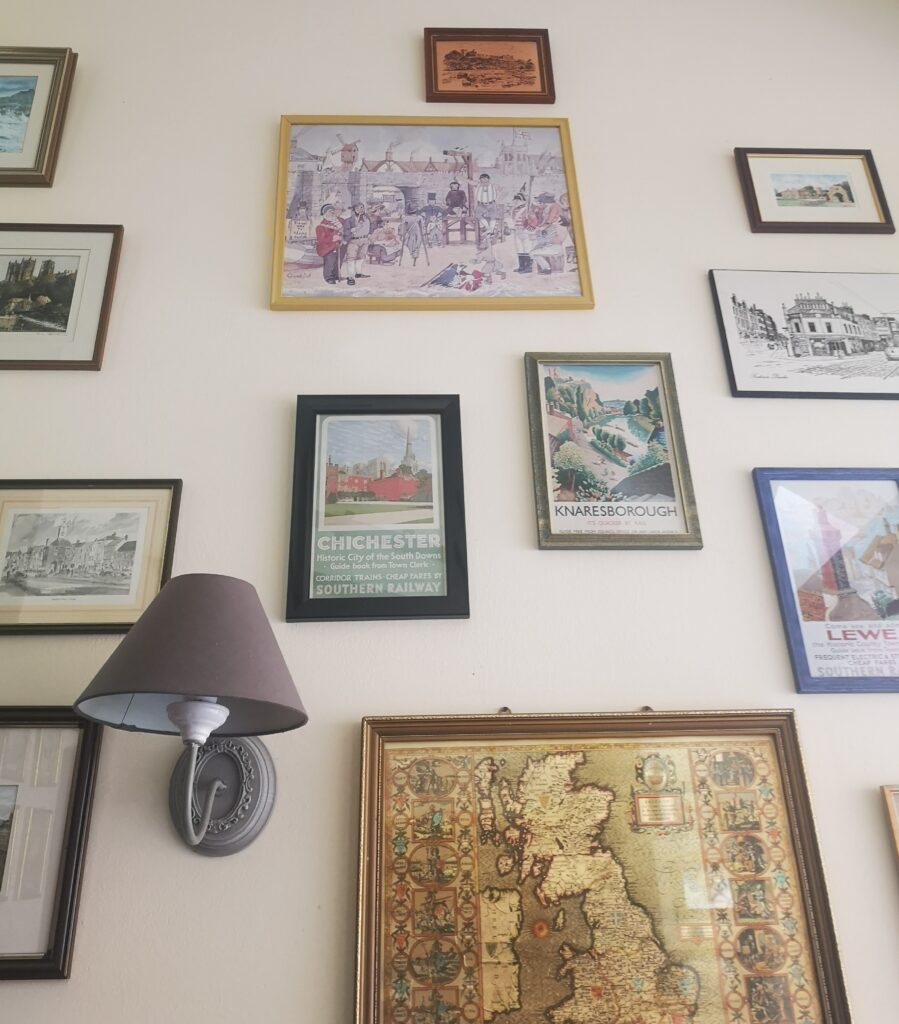 A wall with framed images of various English places and maps