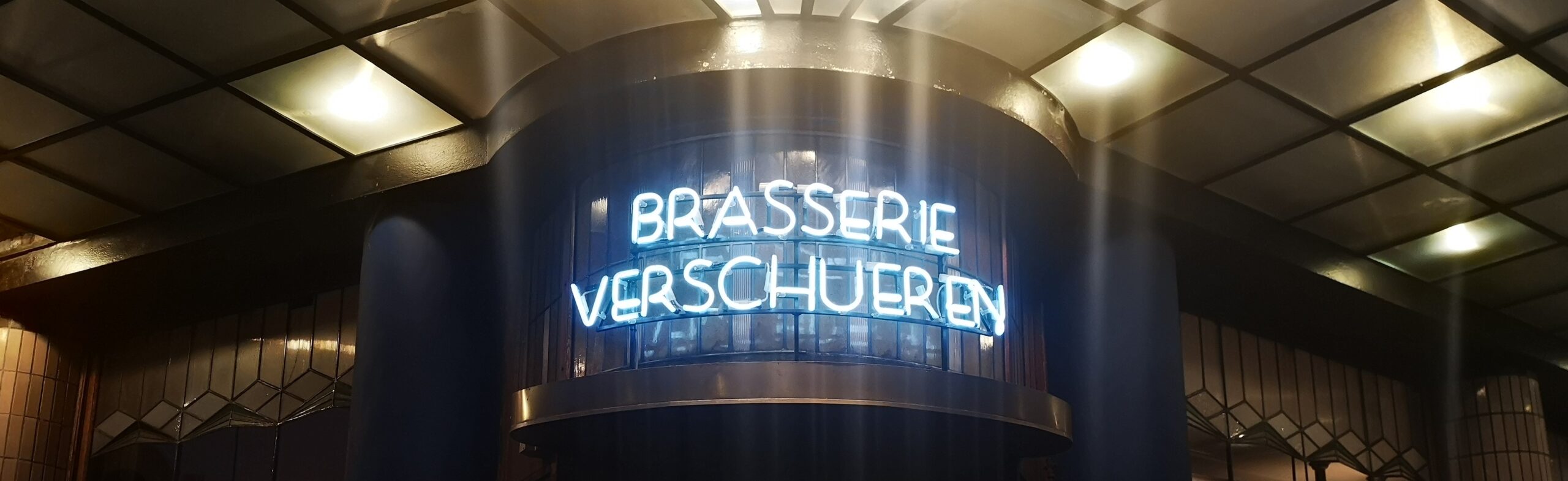 The neon letters spelling out the name of Brasserie Verschueren on the outisde of the building.