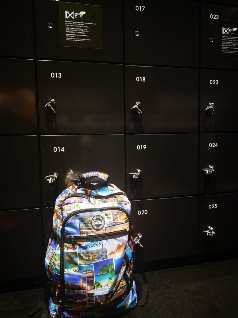 A large backpack on the floor in front of some black lockers, part of the facilities at the Top Tokyo Attraction.