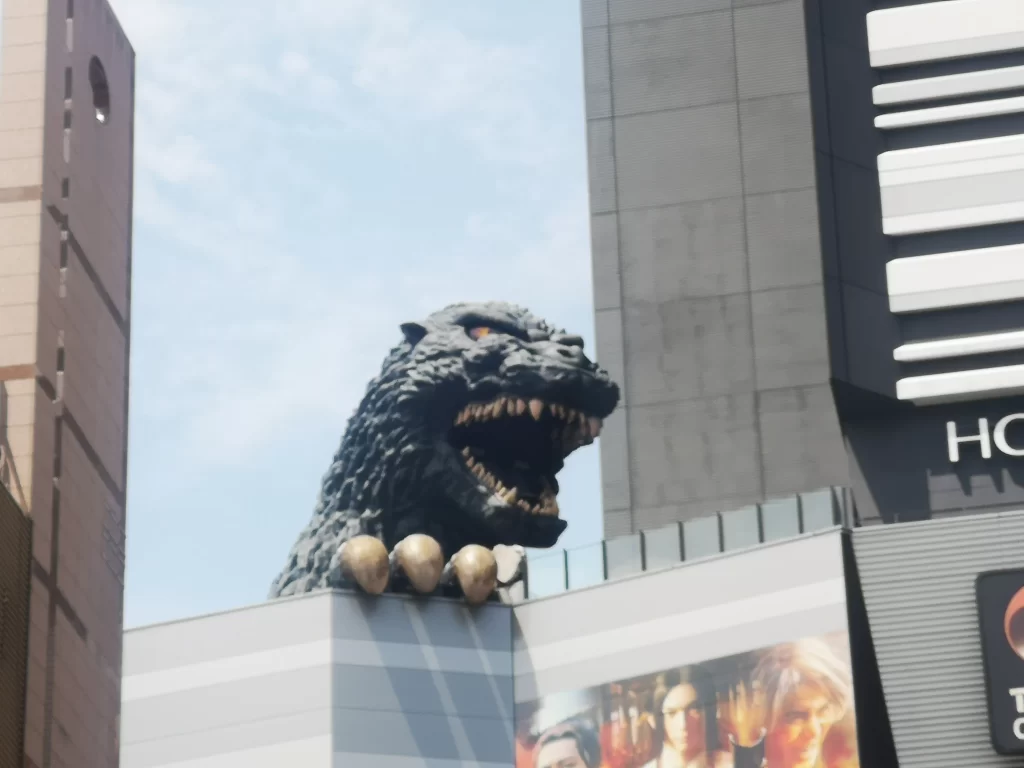 Arguably not a Top Tokyo Attraction, the head of giant reptile Godzilla and claw appearing over a tall building in Tokyo.