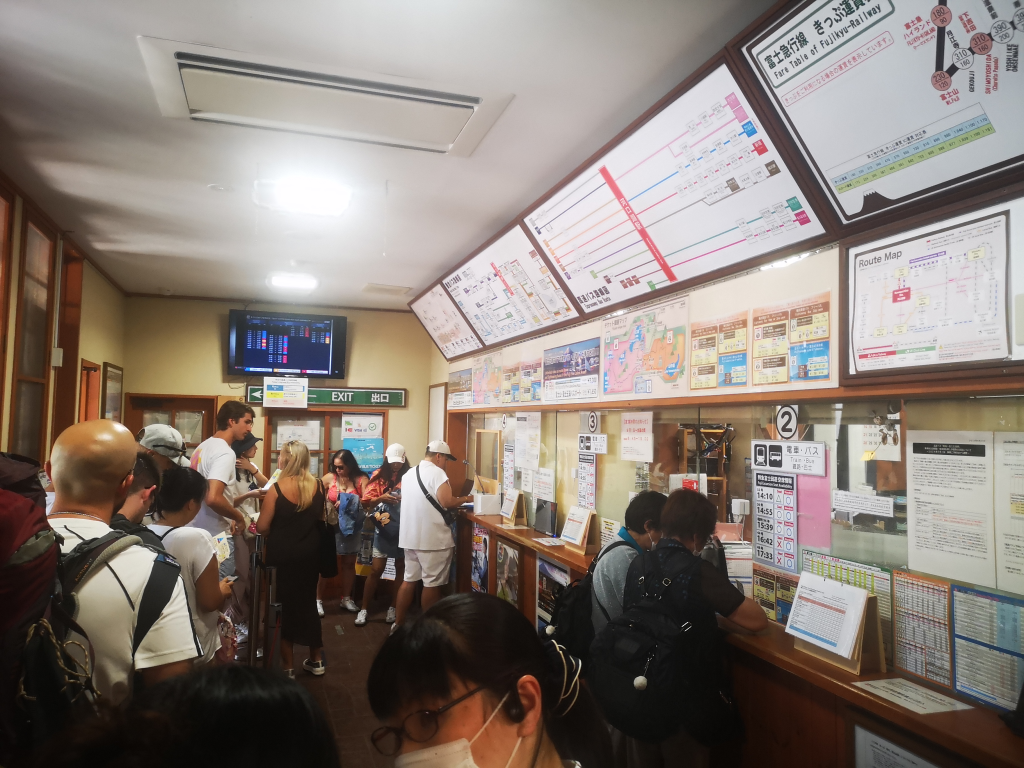 Lots of people queuing in a small ticket office.